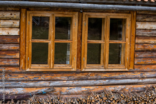 Traditional log house insulated with moss  wooden windows   firewood with a broom.