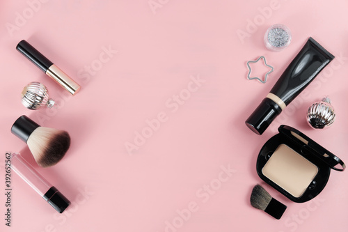 set with makeup products and Christmas decor on pink background. Space for text. holiday gift for women. lipstick  compact powder and shining balls. foundation and mascara.powder brush.