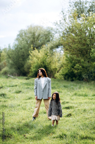 Mom and daughter have fun together. Weekend in nature near the forest in the grass