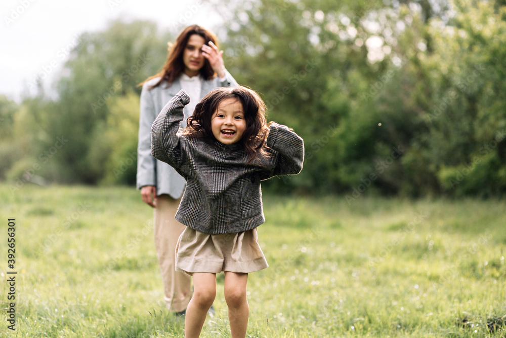 Mom and daughter have fun together. Weekend in nature near the forest in the grass Mom and daughter have fun together. Weekend in nature near the forest in the grass