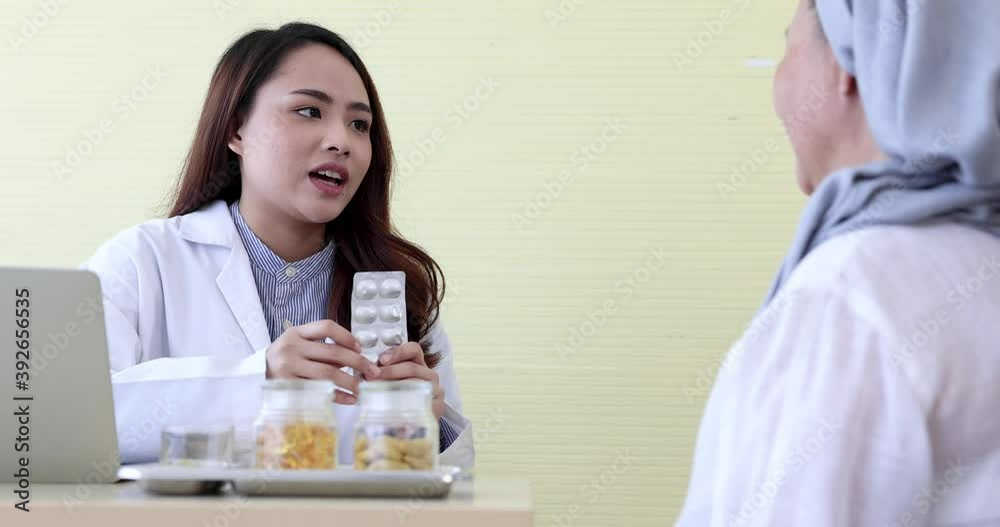 Asian female doctor prescribing medication to elderly patient. Asian female doctor prescribing medication to elderly patient.