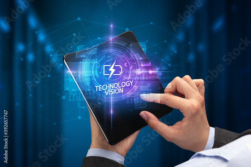 Businessman holding a foldable smartphone with TECHNICAL inscription, new technology concept TECHNOLOGY VISION