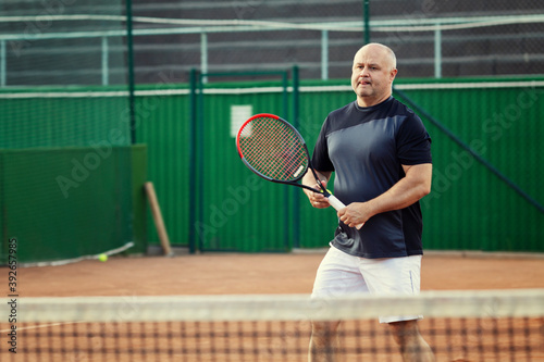 An aged man plays tennis on the court. Active lifestyle and health.