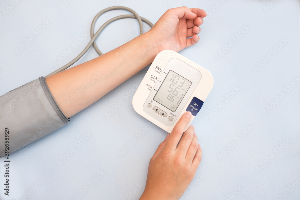 Pressure measurement. A woman takes care of her health by checking her blood pressure and pulse on her hand. Measure your blood pressure and pulse yourself. blue background Pressure measurement. A woman takes care of her health by checking her blood pressure and pulse on her hand. Measure your blood pressure and pulse yourself. blue background