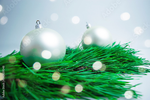 White balls and green pine branches close up  with bokeh on white background. Christmas or New Year holiday greeting card.