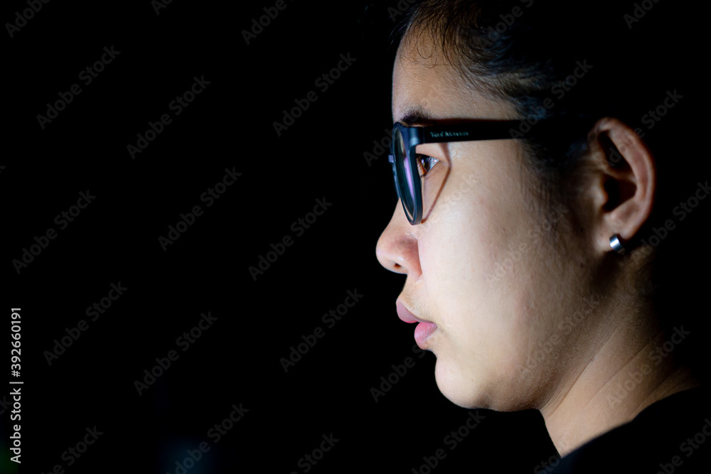 Computer online internet addiction young woman staring at computer screen late at night in dark room. Asian businesswoman working overtime at office desk using blue light glasses eye strain care Computer online internet addiction young woman staring at computer screen late at night in dark room. Asian businesswoman working overtime at office desk using blue light glasses eye strain care