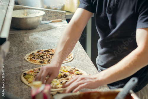 Pizza maker prepares pizza toppings. The cook in the kitchen prepares pizza.