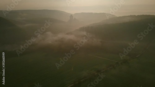 Aerial view of the medieval castle Karlstejn situated on the top of a hill, surrounded by forest in autumn. Valley and forest covered by fog in the morning photo