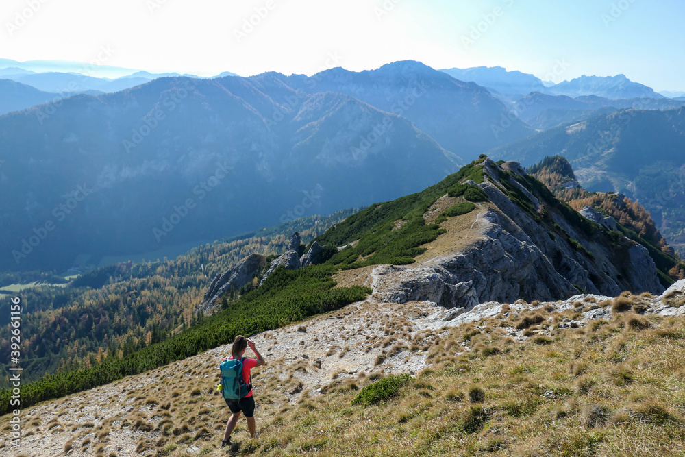 Woman hiking along a mountain ridge in Hochschwab region in Austrian Alps. Endless mountain chains in front. Massive Alps. Autumn vibes in the mountains. Idyllic landscape. Freedom and wilderness