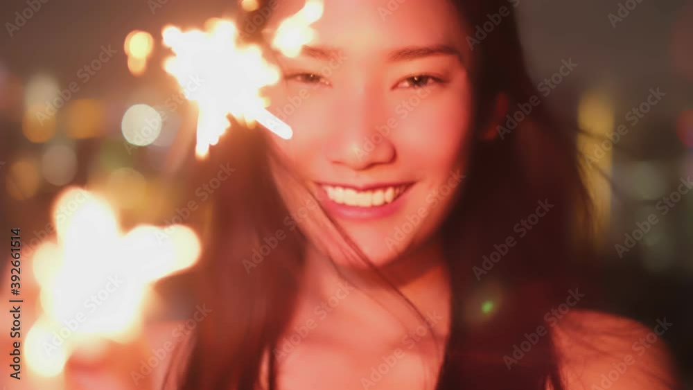 Young asian woman with sparklers is dancing and celebrating a new year. Fireworks, bengal lights in slow motion. Having fun at rooftop in the city.close up sparklers portrait. Young asian woman with sparklers is dancing and celebrating a new year. Fireworks, bengal lights in slow motion. Having fun at rooftop in the city.close up sparklers portrait.