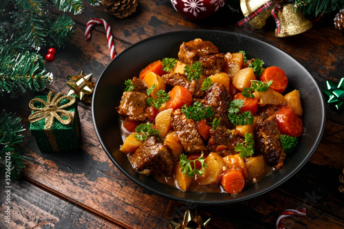 Christmas Beef Stew with decoration, gifts, green tree branch on wooden rustic table