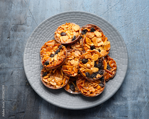 Chocolate Florentines cookies with almond and grapes on grey plate photo