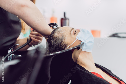 Woman with face mask in a hair salon during har wash