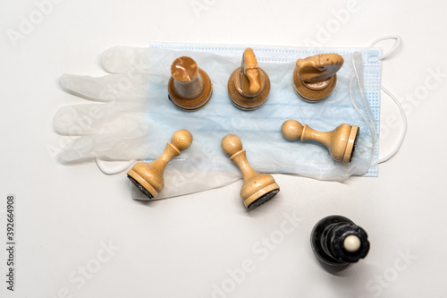 wooden chess pieces on a medical mask. Black's Queen is watching