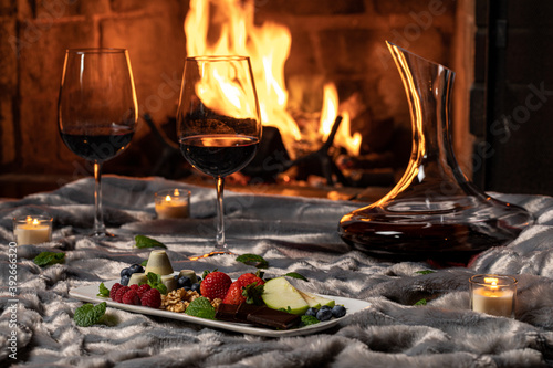 Red wine at fireplace with strawberries on a blanket