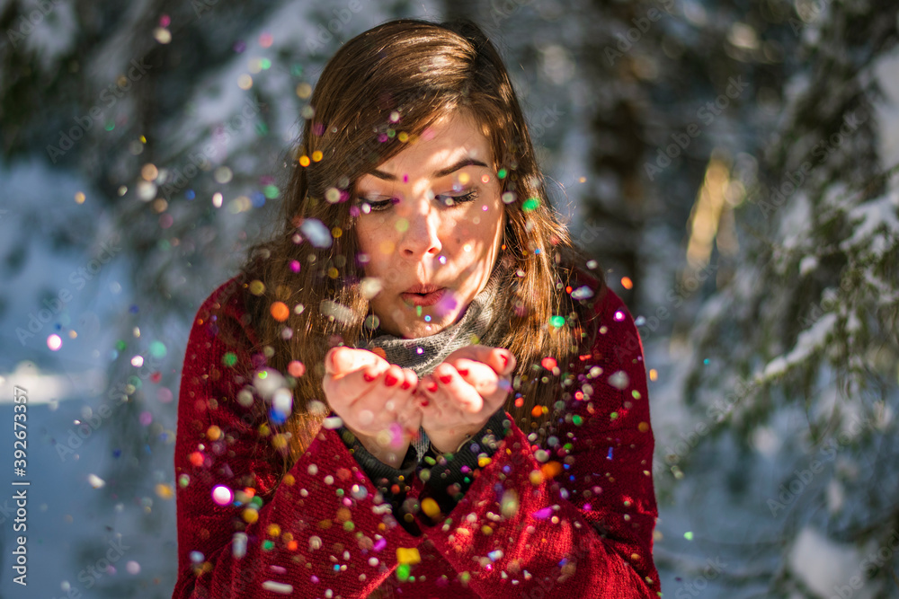 Christmas special portrait of an European cheerful woman blowing colourful objects during holidays Christmas special portrait of an European cheerful woman blowing colourful objects during holidays