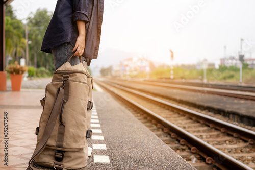 Close up woman traveler hands standing and waiting train at railway station and holding backpack. © C_Production