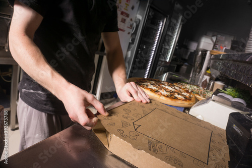 Man packing pizza in a box. Pizza in a cardboard box.