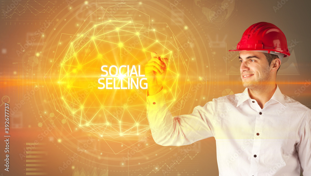 Handsome businessman with helmet drawing SOCIAL SELLING inscription, social construction concept Handsome businessman with helmet drawing SOCIAL SELLING inscription, social construction concept