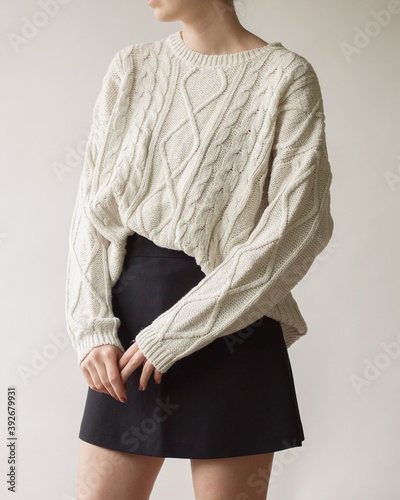 Принти на полотні Young woman wearing stylish outfit with white chunky sweater and mini skirt isolated on white background