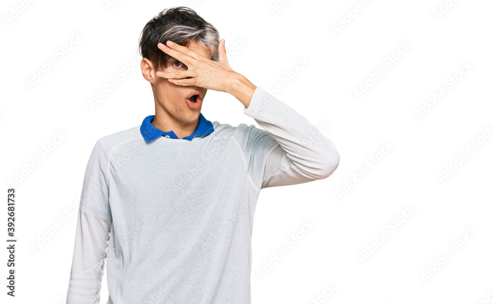 Young hispanic man wearing casual clothes peeking in shock covering face and eyes with hand, looking through fingers with embarrassed expression. Young hispanic man wearing casual clothes peeking in shock covering face and eyes with hand, looking through fingers with embarrassed expression.