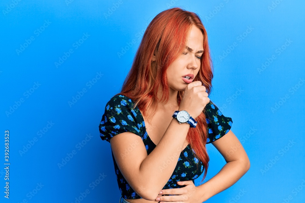 Young beautiful redhead woman wearing casual clothes over blue background feeling unwell and coughing as symptom for cold or bronchitis. health care concept. Young beautiful redhead woman wearing casual clothes over blue background feeling unwell and coughing as symptom for cold or bronchitis. health care concept.
