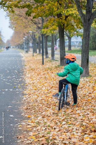 Beautiful autumn shot of a child on a bike looking at something