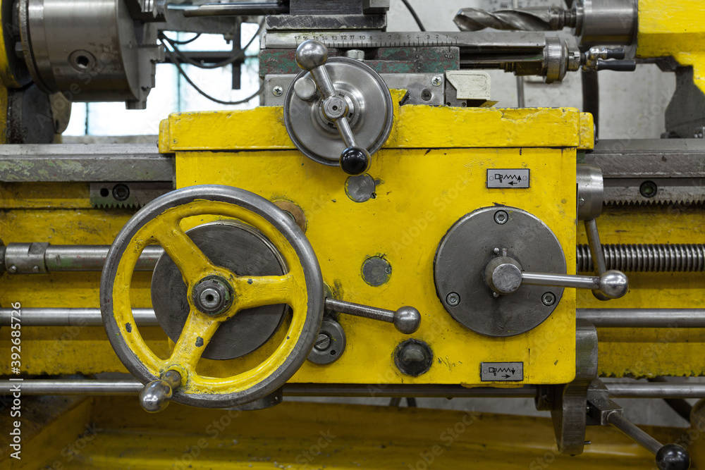 Old yellow lathe machine with a lot of handles.