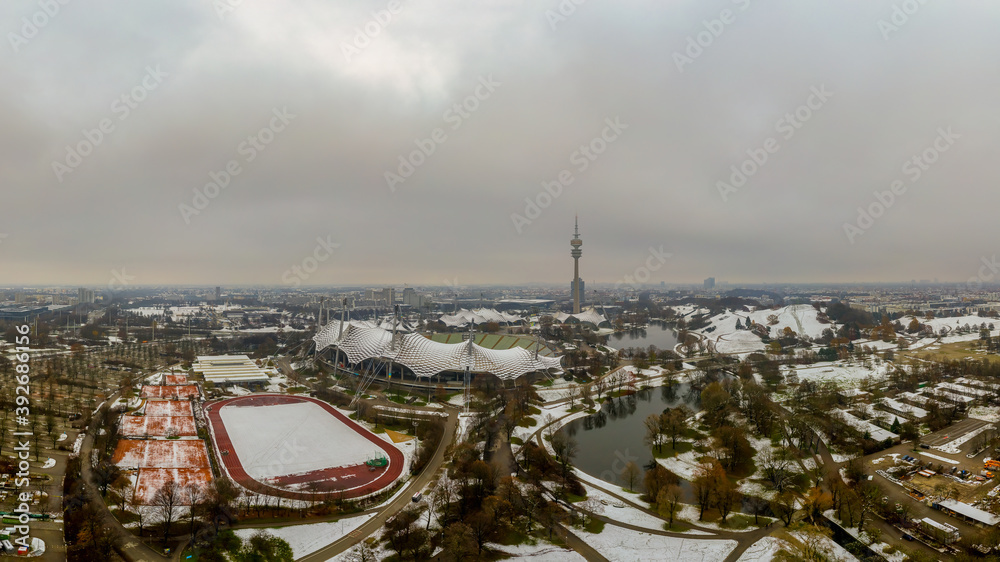 Winter in Munich, snow covered park in the heart of the bavarian metropole, a panoramic view at the olympic park with its tower and lake.