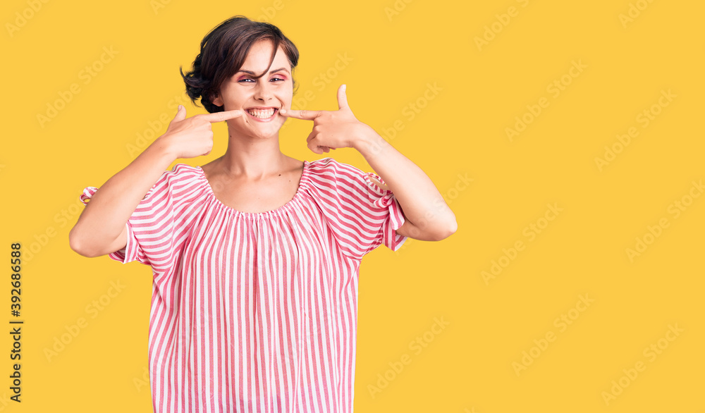 Beautiful young woman with short hair wearing casual summer clothes smiling cheerful showing and pointing with fingers teeth and mouth. dental health concept.