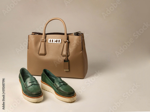 Women's shoes with thick green leather soles against the background of a bag of light brown leather