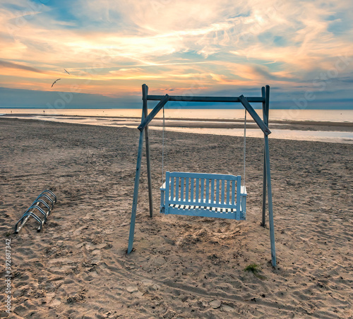 Sandy beach of the Baltic Sea with decorative swing for sport and resting act...