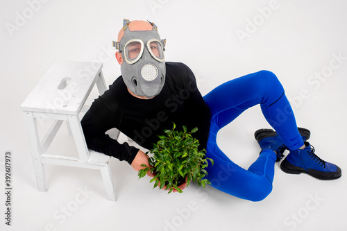 Funny strange man in respirator posing with flower in the pot over white background