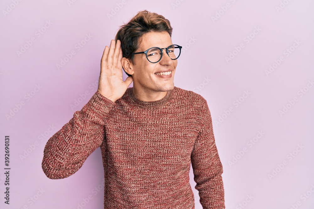 Handsome caucasian man wearing casual sweater and glasses smiling with hand over ear listening an hearing to rumor or gossip. deafness concept. Handsome caucasian man wearing casual sweater and glasses smiling with hand over ear listening an hearing to rumor or gossip. deafness concept.