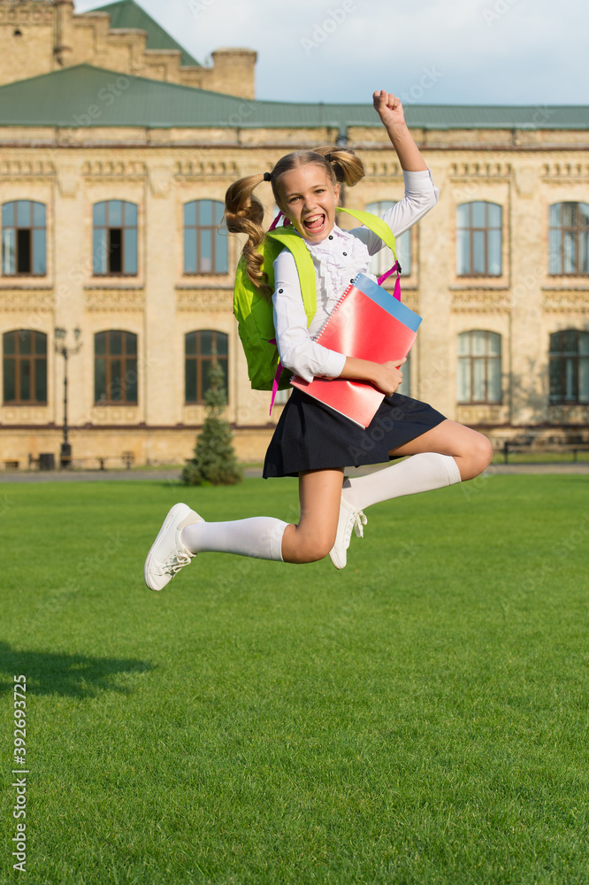 Energetic child in formal uniform with study books backpack jump in schoolyard happy celebrating, back to school