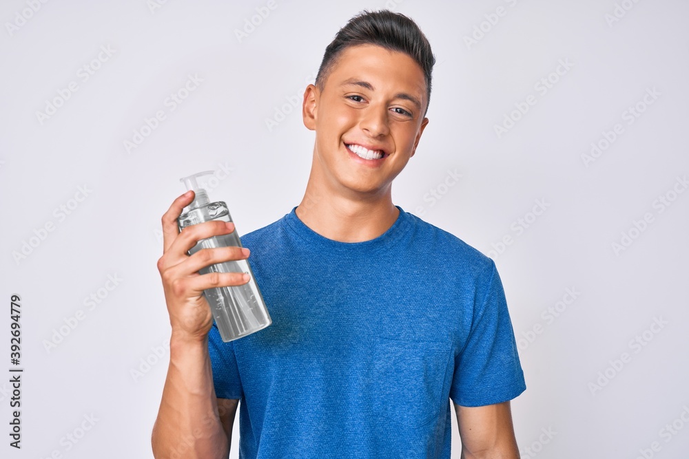 Young hispanic boy using hand sanitizer gel looking positive and happy standing and smiling with a confident smile showing teeth Young hispanic boy using hand sanitizer gel looking positive and happy standing and smiling with a confident smile showing teeth