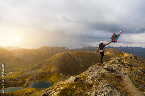Young happy backpacker woman on top of the mountain. Traveler hiking on mountains at the sunset. Concept about lifestyle, sport, nature and travel. 