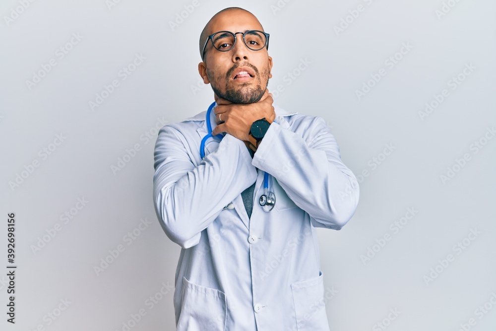 Hispanic adult man wearing doctor uniform and stethoscope shouting suffocate because painful strangle. health problem. asphyxiate and suicide concept. Hispanic adult man wearing doctor uniform and stethoscope shouting suffocate because painful strangle. health problem. asphyxiate and suicide concept.