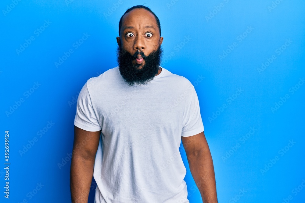 Young african american man wearing casual white tshirt making fish face with lips, crazy and comical gesture. funny expression. Young african american man wearing casual white tshirt making fish face with lips, crazy and comical gesture. funny expression.