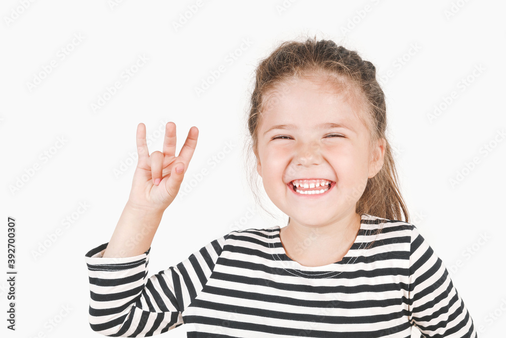 Laughing girl with three fingers up, showing Number three. Close up of posing little girl wearing a striped shirt, looking at the camera on an isolated background. Learning with a fun concept. Laughing girl with three fingers up, showing Number three. Close up of posing little girl wearing a striped shirt, looking at the camera on an isolated background. Learning with a fun concept.