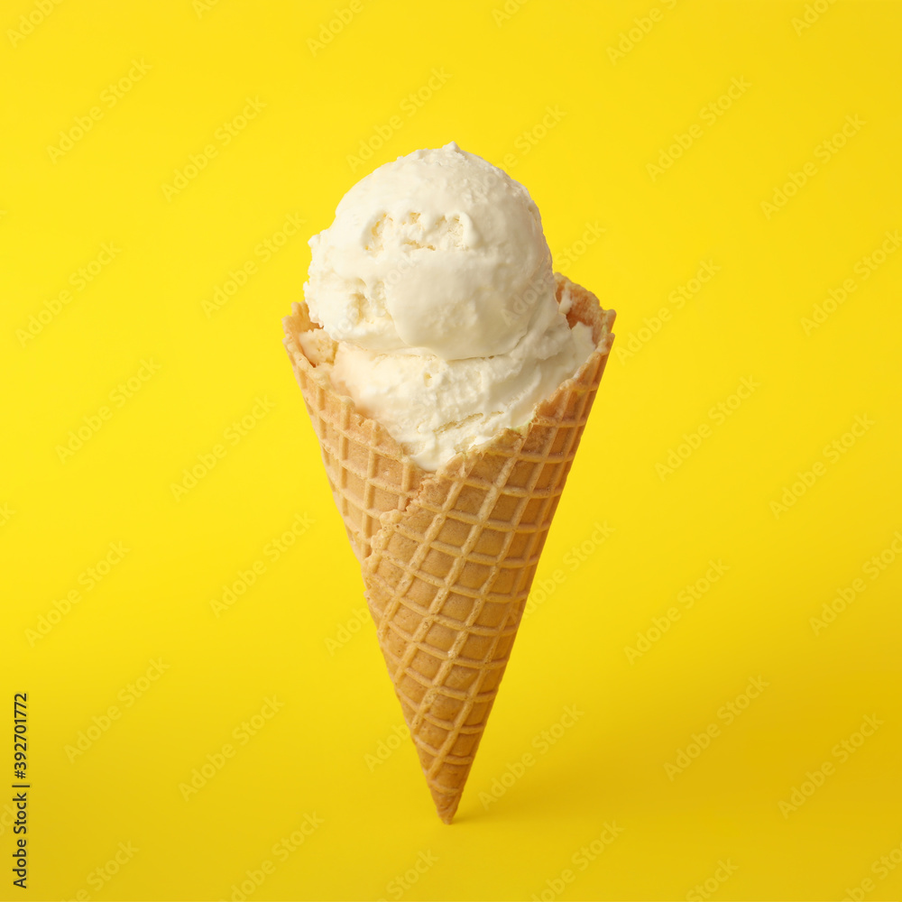 Delicious ice cream in waffle cone on yellow background Delicious ice cream in waffle cone on yellow background
