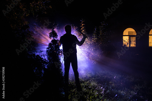 strange light in a dark forest at night. Silhouette of person standing in the dark forest with light. Horror halloween concept. strange silhouette in a dark spooky forest at night