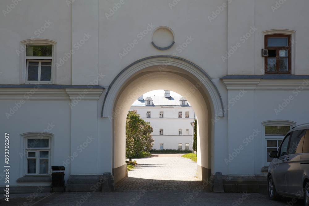 White wall with an arch leading to a sunny courtyard.