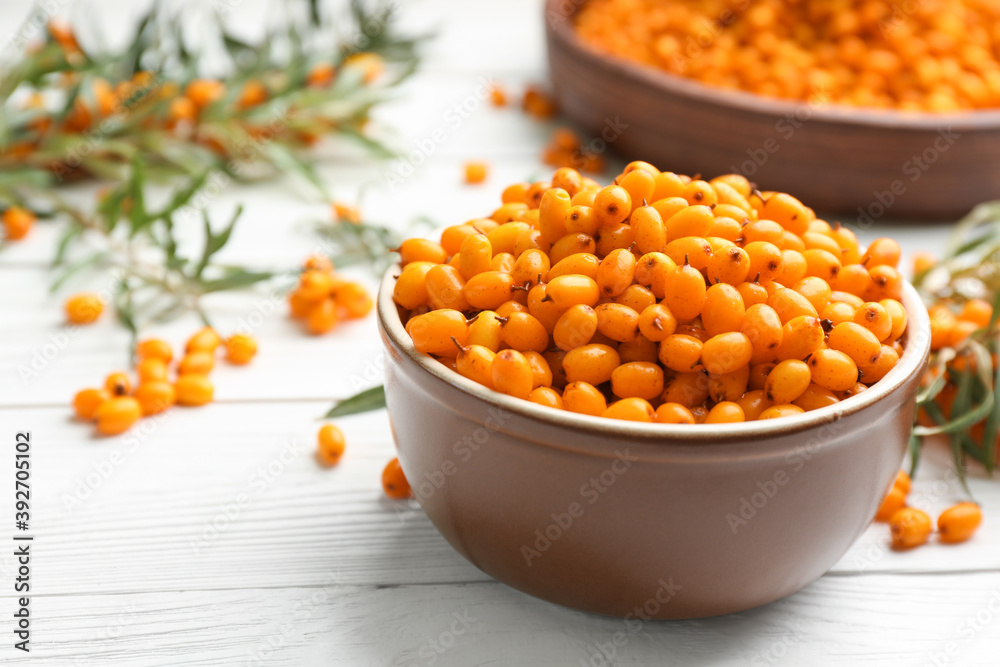 Fresh ripe sea buckthorn in bowl on white wooden table Fresh ripe sea buckthorn in bowl on white wooden table