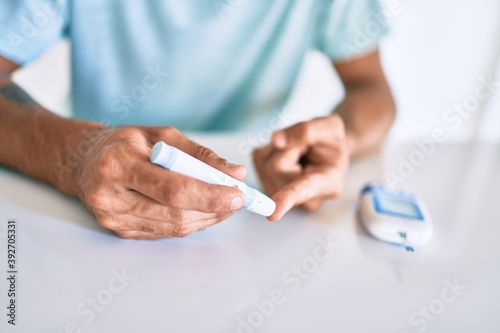 Young hispanic diabetic man measuring glucose level at home