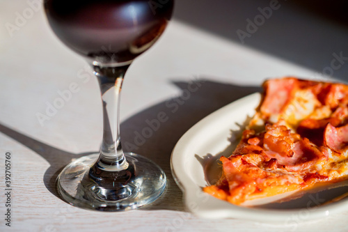 Close up of Glass of wine next to a slice of pizza