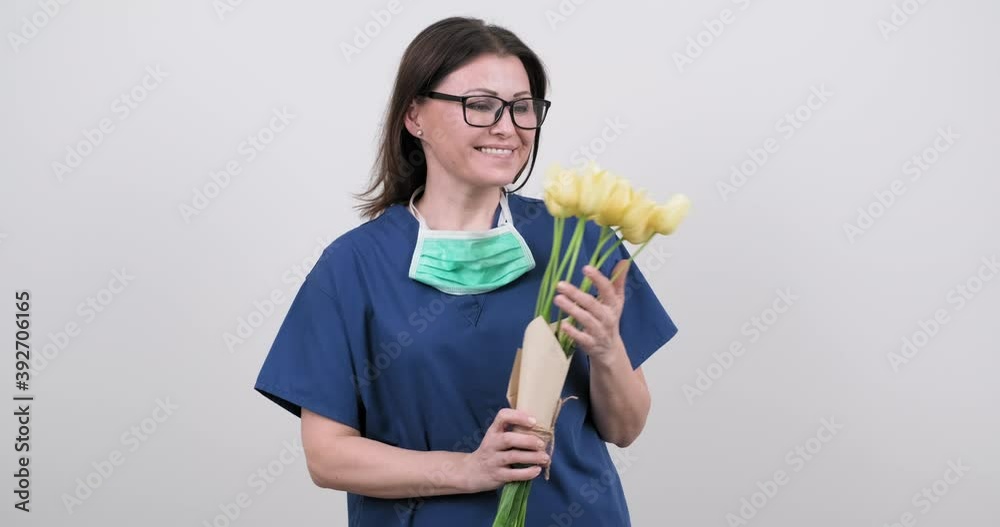 Woman doctor nurse in protective medical mask with bouquet of flowers on white background. Woman doctor nurse in protective medical mask with bouquet of flowers on white background.