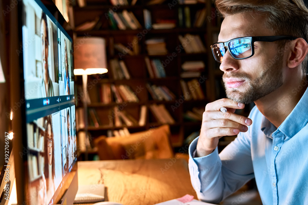 Serious young businessman wearing glasses looking at pc computer screen working online by video conference call having remote social distance online team virtual chat meeting concept, close up view. Serious young businessman wearing glasses looking at pc computer screen working online by video conference call having remote social distance online team virtual chat meeting concept, close up view.