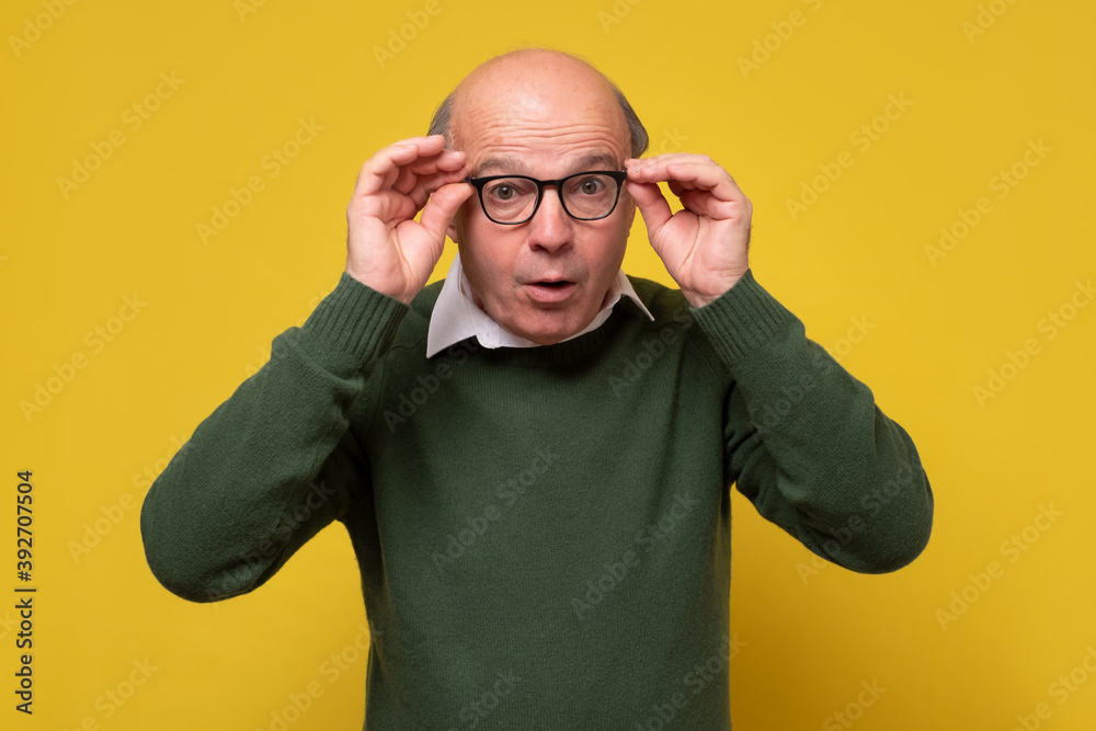 Shocked worried senior man keeping mouth opened. Studio shot on yellow wall. Shocked worried senior man keeping mouth opened. Studio shot on yellow wall.
