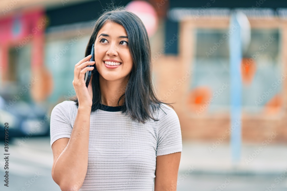 Young hispanic woman smiling happy talking on the smartphone at the city. Young hispanic woman smiling happy talking on the smartphone at the city.